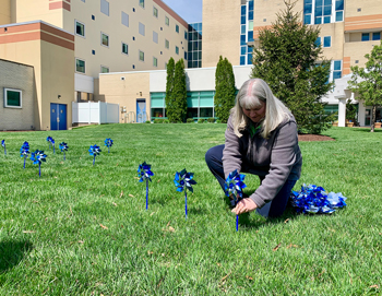 Beebe team member Sonia Manning places a pinwheel on the front lawn of the Margaret H. Rollins Lewes Campus on Tuesday, April 16. 