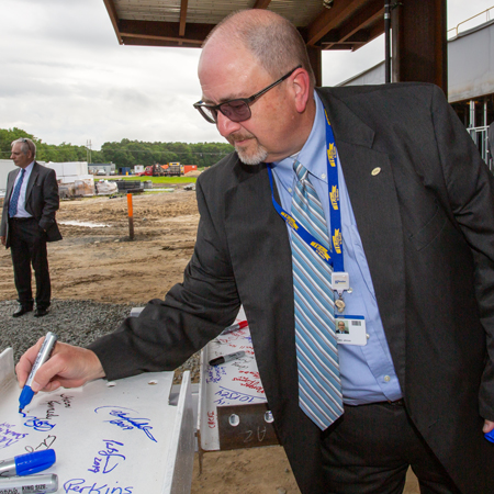 Rick Schaffner signs the beam at the South Coastal Health Campus near Millville.