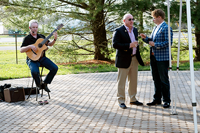 Paul Cullen performs as Tom Protack, Vice President of Development, and Andy Staton speak during the Beebe Medical Foundation patio party.
