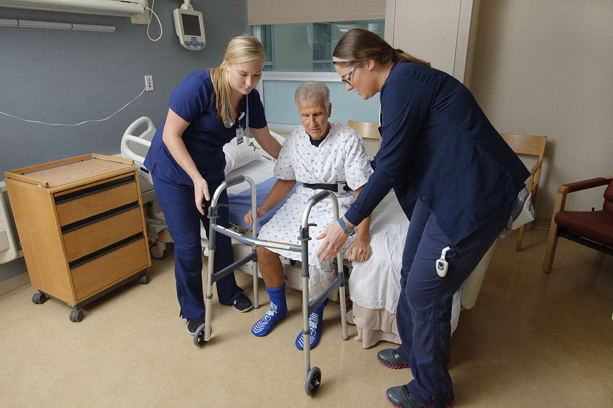 Orthopaedics patient receives help standing up to prevent a fall.